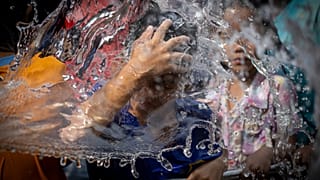 Ein Mann reagiert, als er während des Songkran-Wasserfestes zur Feier des thailändischen Neujahrs mit Wasser bespritzt wird, 13. April 2025