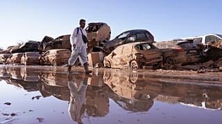 Um homem passa por carros empilhados depois das inundações em Catarroja, que deixaram centenas de mortos e desaparecidos na região de Valência, em Espanha.