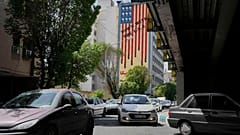 Fahrzeuge fahren vor einem Anti-US-Wandbild in der Innenstadt von Teheran, Iran, Sonntag, 13. April 2025. (AP Photo/Vahid Salemi)