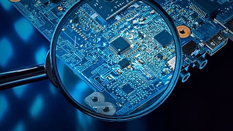 View of a chip on a computer's motherboard through a magnifying glass.