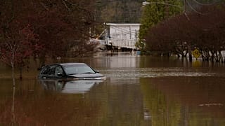 Un hombre camina junto a coches apilados tras las inundaciones de Catarroja que dejaron cientos de muertos o desaparecidos en la región de Valencia, en España.