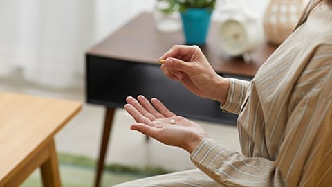 A woman takes a pill.