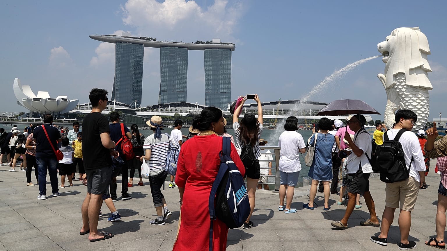 Turistas tiram fotografias junto ao Merlion em frente ao Marina Bay Sands, 7 de junho de 2018