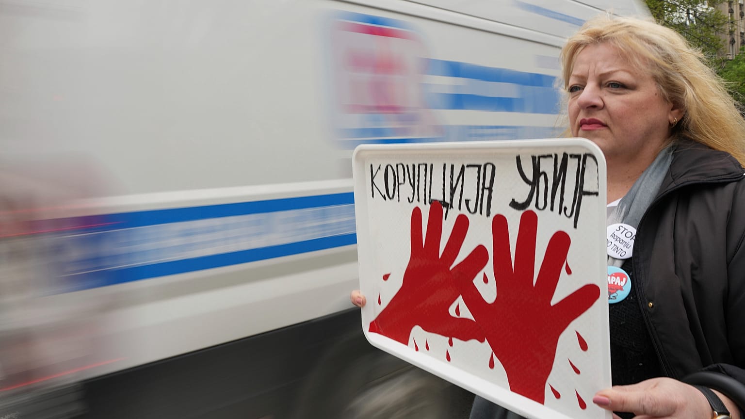 Une femme tient une banderole sur laquelle on peut lire "La corruption tue" lors d'une manifestation devant le siège de la télévision publique à Belgrade, le 15 avril 2025.