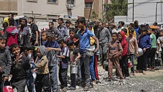 Palestinesi in attesa di cibo donato presso un centro di distribuzione a Nuseirat, 11 aprile 2025
