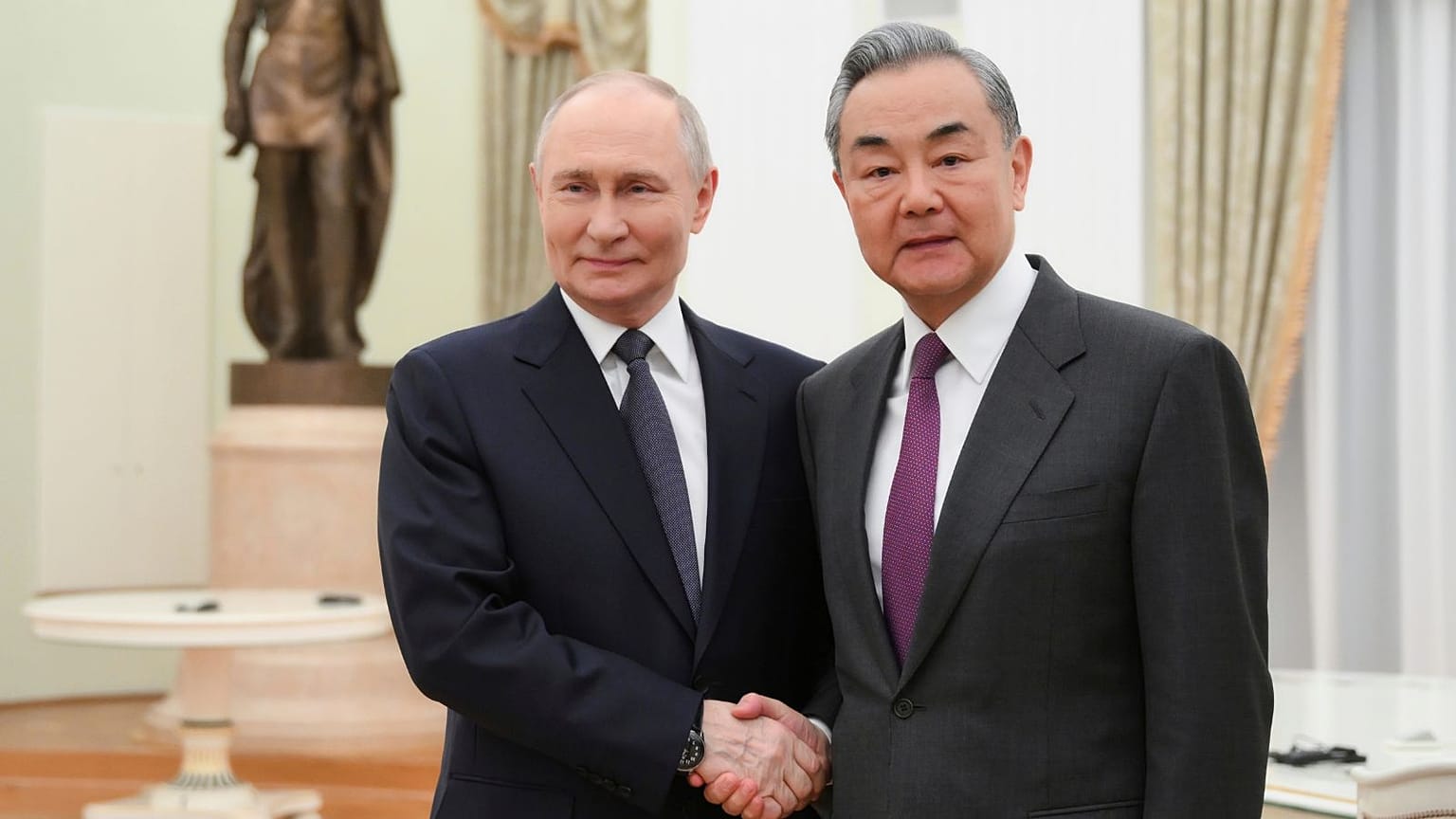 Le président russe Vladimir Poutine et le ministre chinois des Affaires étrangères Wang Yi se serrent la main lors de leur rencontre au Kremlin à Moscou.