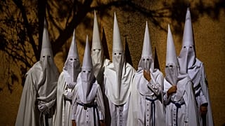 Penitents from "La Paz" brotherhood pose for a photo, requested by a relative of one of them, before taking part in a procession in Seville.