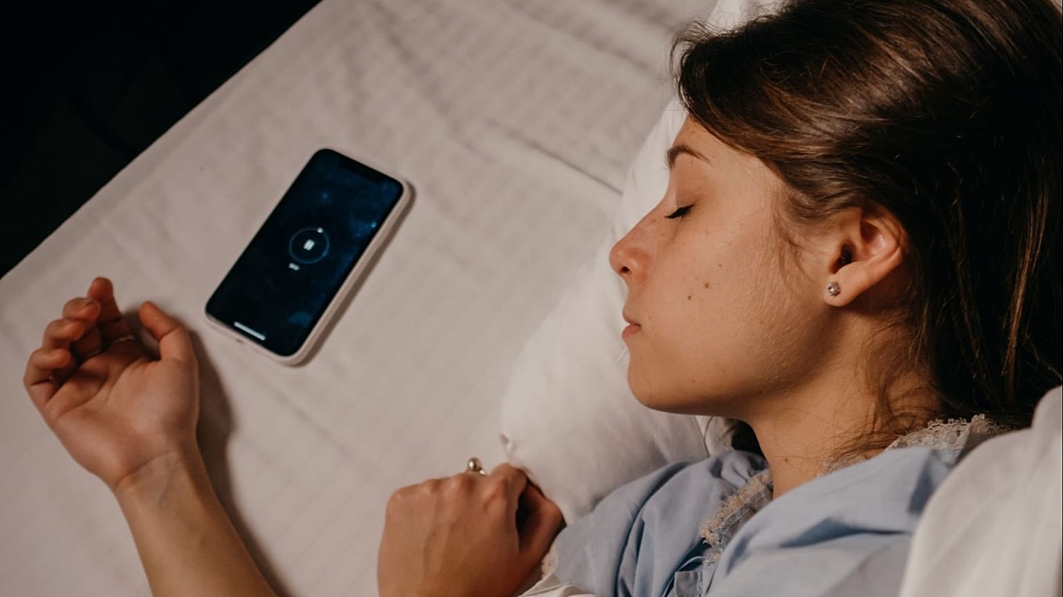 Un'adolescente dorme accanto al suo telefono.
