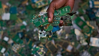 Trabalhador recolhe placas de telemóveis para colocá-las num saco para a reciclagem perto de Nairobi, no Quénia