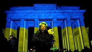 Demonstranten erreichen das in ukrainischen Farben beleuchtete Brandenburger Tor während einer Demonstration gegen den Krieg Russlands gegen die Ukraine.