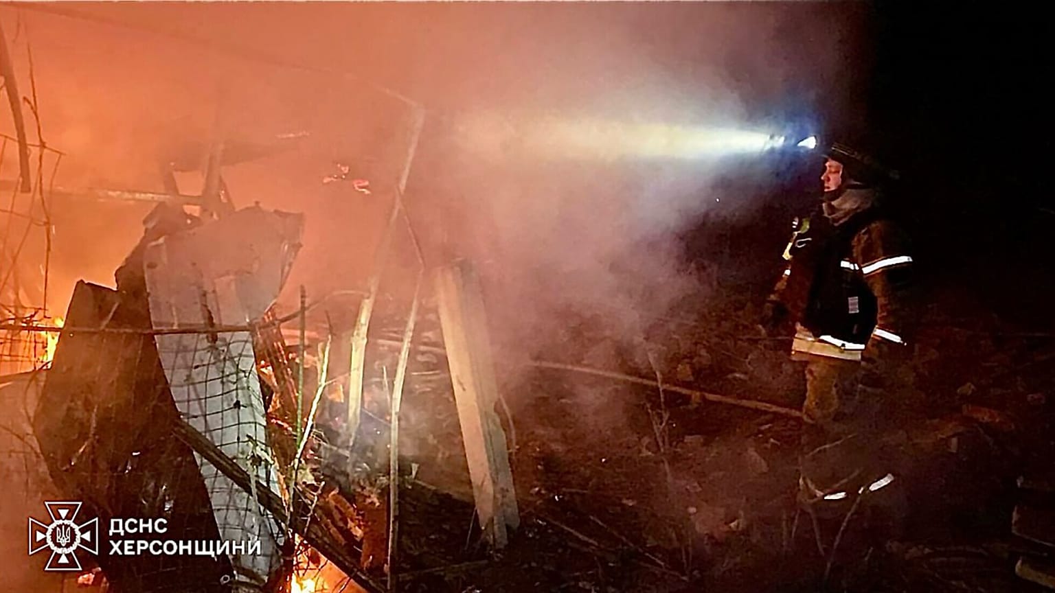Les pompiers éteignent l'incendie dans des maisons privées après une attaque de bombe aérienne guidée russe à Kherson, le 15 mars 2025