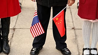 Egy férfi kínai és amerikai zászlóval a kezében Donald Trump 2017-es pekingi látogatásakor