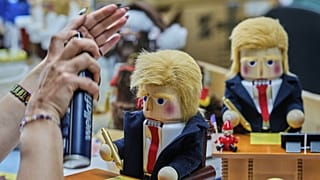 Uma mulher usa spray de cabelo para fixar o cabelo de um quebra-nozes intitulado 'Mesa Resoluta do Presidente' na fábrica Steinbach-Volkskunst em Marienberg, 15 de abril de 2025