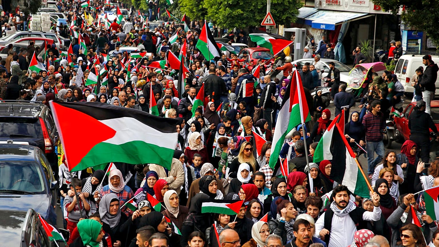 فلسطينيون ولبنانيون يرفعون الأعلام الفلسطينية خلال مسيرة في شوارع بيروت بعد صلاة الجمعة.