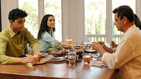 A family eats dinner around the table.
