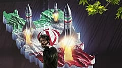 Ein Passant geht an einem Banner vorbei, das den Abschuss von Raketen von der iranischen Landkarte im Norden Teherans zeigt, 19. April 2024