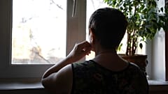 Eine Frau schaut aus ihrem Fenster.