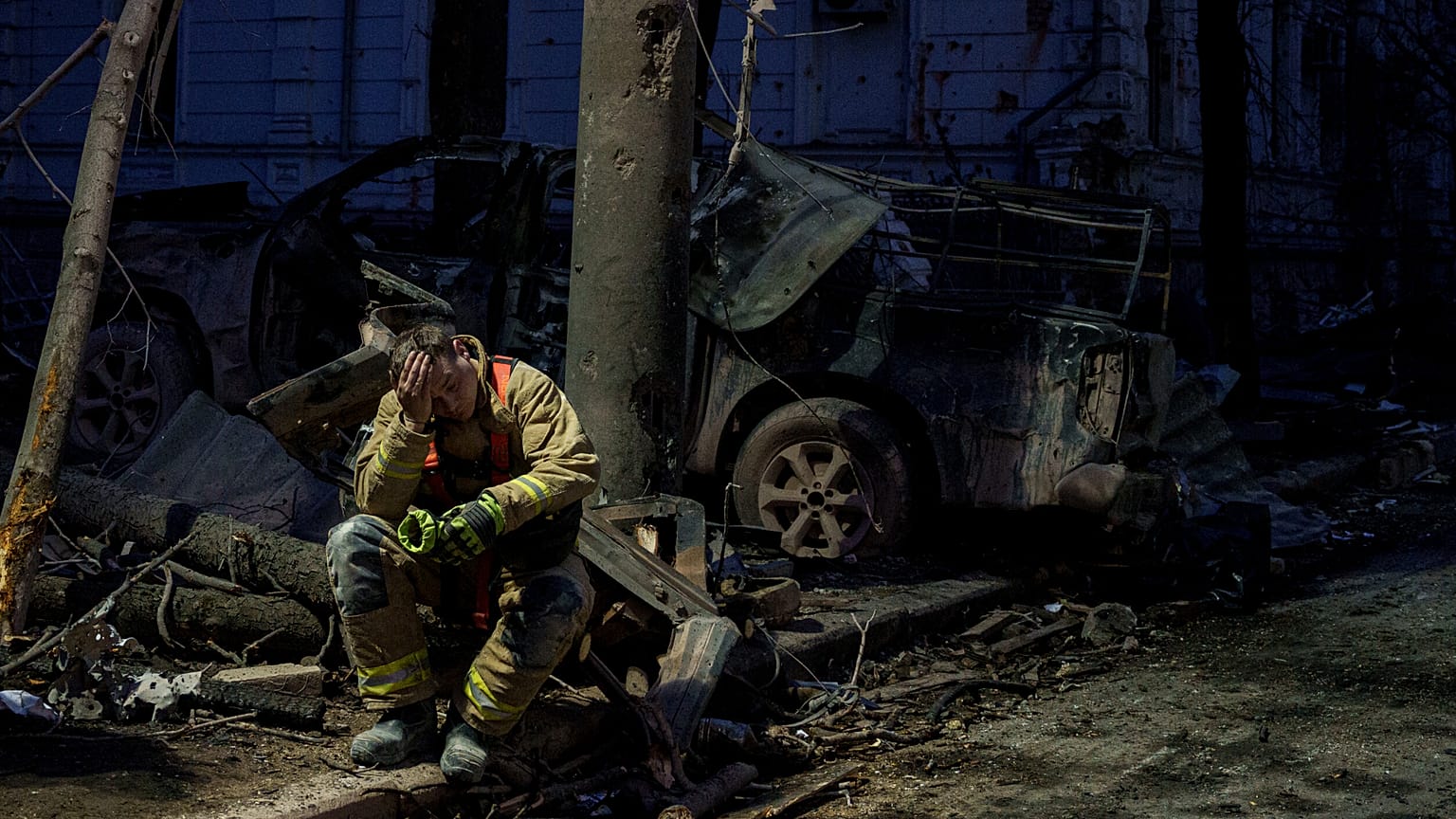 A rescue worker rests near a university building destroyed by a Russian missile strike on Sumy, 13 April, 2025