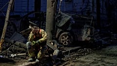 A rescue worker rests near a university building destroyed by a Russian missile strike on Sumy, 13 April, 2025
