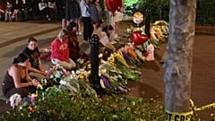 Zaimprowizowany miejsce pamięci i studenci niosący kwiaty wieczorem w pobliżu centrum kampusu Florida State, z widokiem na budynek Student Union