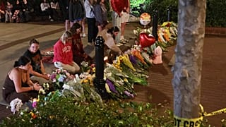 Zaimprowizowany miejsce pamięci i studenci niosący kwiaty wieczorem w pobliżu centrum kampusu Florida State, z widokiem na budynek Student Union