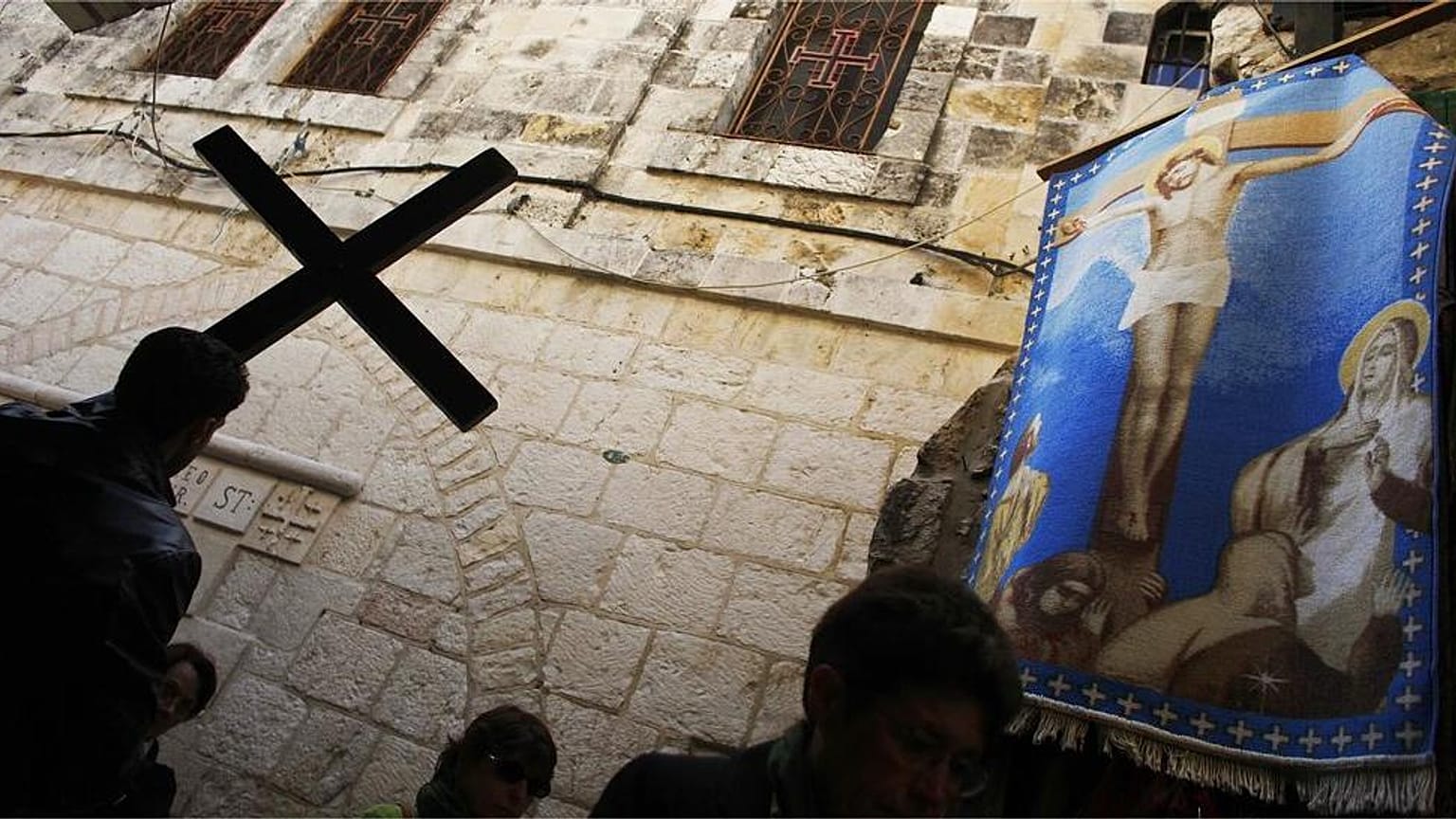 مصلي مسيحي يحمل صليبا باتجاه كنيسة القبر المقدس، خلال موكب الجمعة العظيمة في البلدة القديمة في القدس