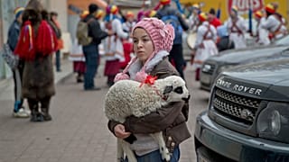 Una mendiga sostiene un cordero mientras los aldeanos de Dofteana, en el norte de Rumanía, celebran un ritual navideño en Bucarest.