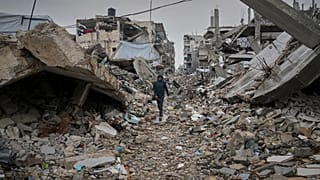صبي فلسطيني يسير في شارع مغطى بأنقاض المنازل والمباني المدمرة في جباليا، شمال قطاع غزة، الجمعة 7 مارس/آذار 2025