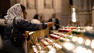 A parishioner lights a candle at St. Patrick's Cathedral in New York, 21 April, 2025