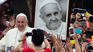 Papa Francesco passa davanti a un suo ritratto mentre arriva per incontrare i giovani dell'Università di Santo Tomas a Manila, nelle Filippine, 18 gennaio 2015