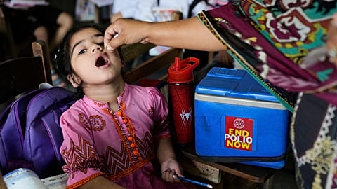 A health worker administers a polio vaccine to a child in a school in Lahore, 21 April, 2025