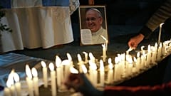 Fedeli accendono candele sotto un ponte dell'autostrada durante la Messa in onore del defunto Papa Francesco nel quartiere Carlos Mugica di Buenos Aires.