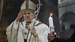 Ein Gläubiger hält während einer Messe zu Ehren des verstorbenen Papstes Franziskus eine Kerze.
