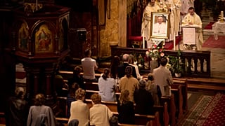 Personas asisten a un servicio religioso por el fallecido Papa Francisco, tras el anuncio de su muerte, en la catedral de San José en Bucarest, Rumanía, lunes 21 de abril de 2025.
