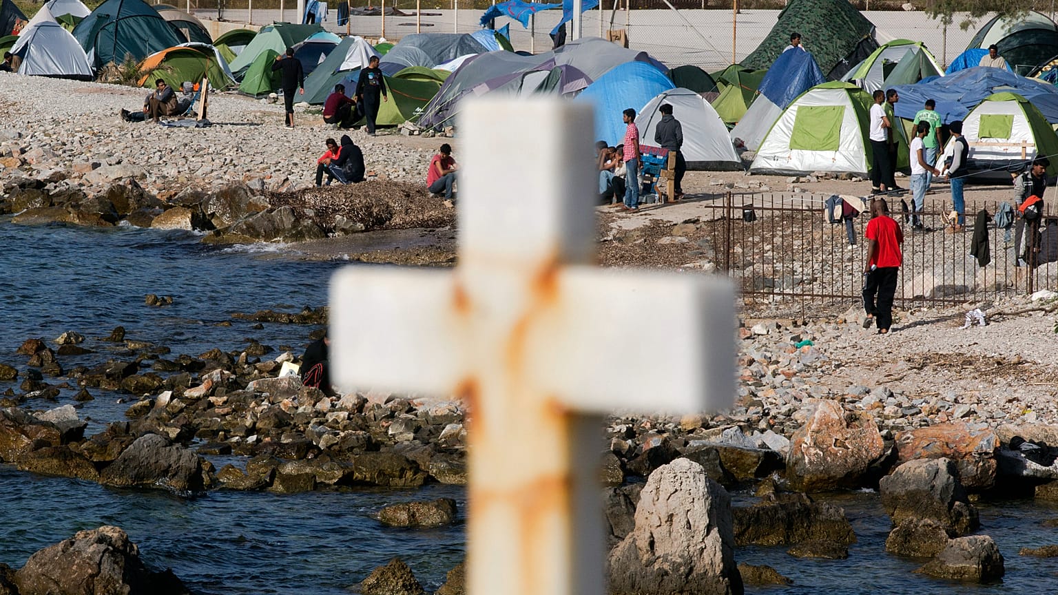 Migranci i uchodźcy idą za krzyżem w obozie założonym przez wolontariuszy w pobliżu portu Mytilini, 15 kwietnia 2016 r.