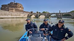 Italienische Polizisten auf einem Schlauchboot patrouillieren zur Sicherheit auf dem Tiber in der Nähe des Vatikans, mit der Burg Sant'Angelo im Hintergrund, Dienstag, 22. April 2025.
