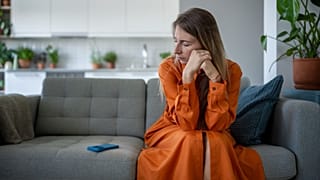 Una mujer sentada en un sofá mira su teléfono.