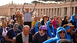 A person holding up the word "Mexico" stands amid the crowd in St Peter's Square at the Vatican, 23 April 2025