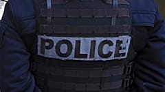 Bir polis memuru, Paris'te Seine Nehri boyunca göçmenleri tahliye eden yetkililerle birlikte çadırların önünde duruyor, 1 Nisan 2025.