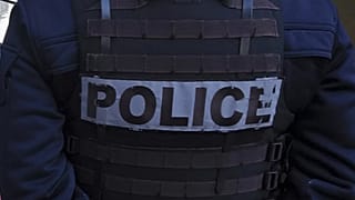 Bir polis memuru, Paris'te Seine Nehri boyunca göçmenleri tahliye eden yetkililerle birlikte çadırların önünde duruyor, 1 Nisan 2025.