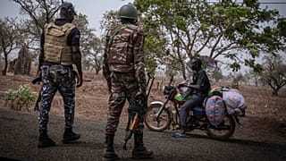 Un agente de policía y un soldado de Benín detienen a un motociclista en un puesto de control a las afueras de Porga, Benín, el 26 de marzo de 2022.