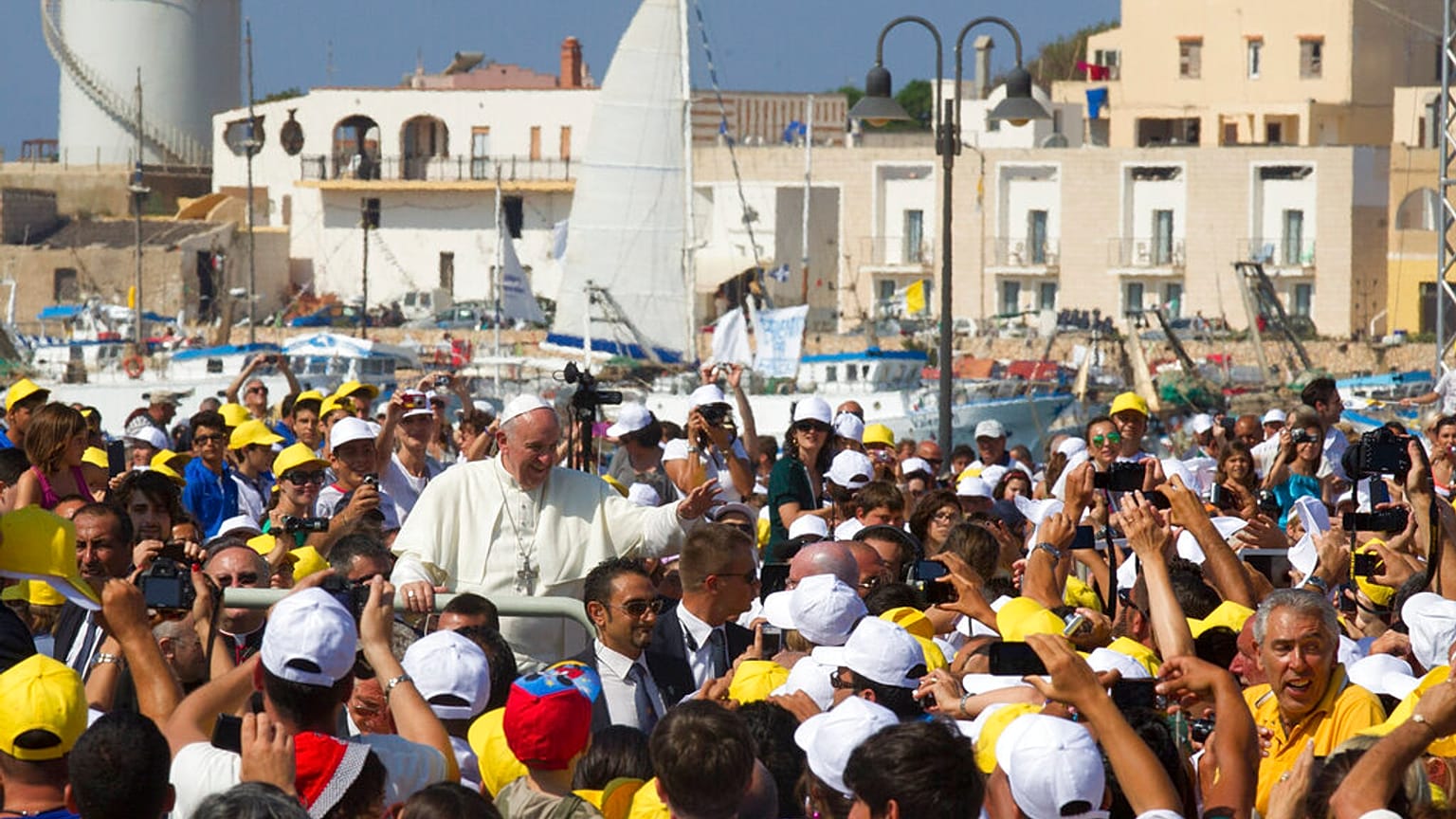 Pope Francis waves to faithful as he is driven through the crowd during his visit to the island of Lampedusa, southern Italy, Monday July 8, 2013. 
