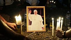 People light candles around a portrait of Pope Francis in East Timor where the late pope led a mass during his visit in 2024, 25 April, 2025