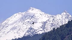 Hegycsúcs emelkedik a völgy felett járőröző katonai helikopter mögött, miután a fegyveresek válogatás nélkül tüzet nyitottak a turistákra az indiai Pahalgam közelében.