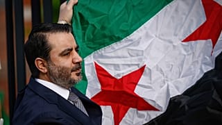 Il ministro degli Esteri siriano Asaad Al-Shibani tiene la bandiera siriana