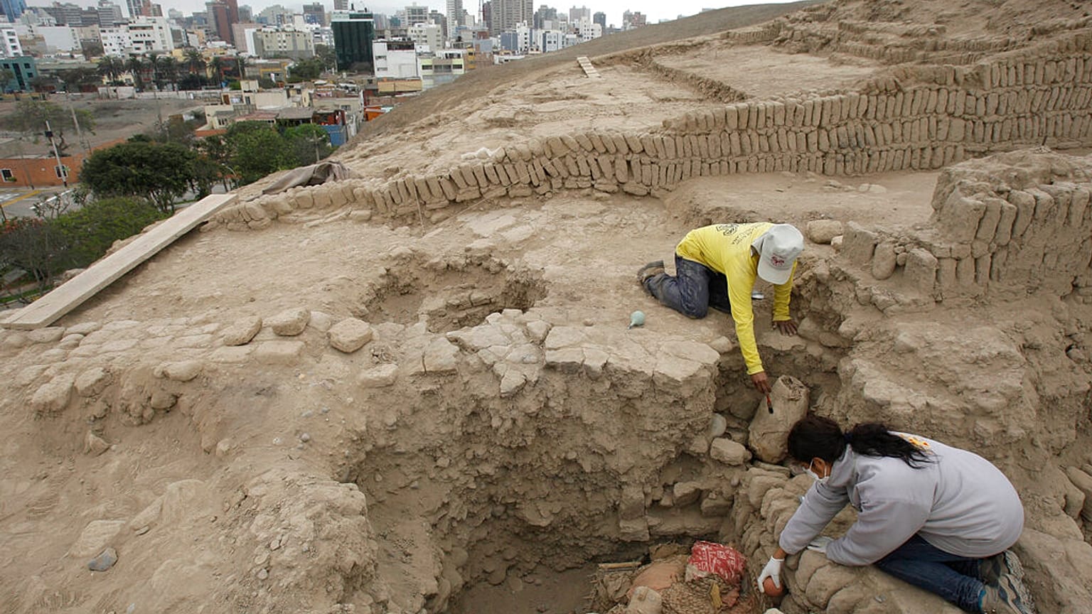 عالمة الآثار غلاديس باز، في الأسفل، ورجل مجهول يعملان في الموقع حيث تم اكتشاف قبر من ثقافة واري القديمة في هرم هوكا بوكلانا في ليما، بيرو، يوم الأربعاء 20 أكتوبر/تشرين الأول 2