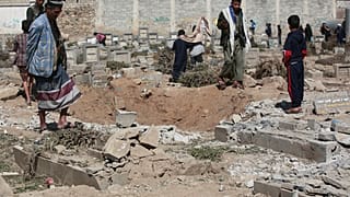 يمنيون يتأملون حفرة ضخمة خلفتها غارة جوية أمريكية استهدفت مقبرة "ماجل الدماح" في العاصمة صنعاء، يوم الأحد 20 أبريل/نيسان 2025
