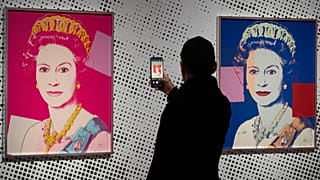 Un hombre toma una imagen de una serigrafía que representa a la reina Isabel II, una de una serie de dieciséis impresiones de cuatro reinas titulada Reigning Queens (Reinas reinantes), 1985, de Andy Warhol.