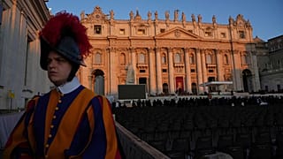 Une garde suisse pontificale se tient devant la basilique Saint-Pierre au lever du soleil avant les funérailles du pape François sur la place Saint-Pierre, le 26 avril 2025.