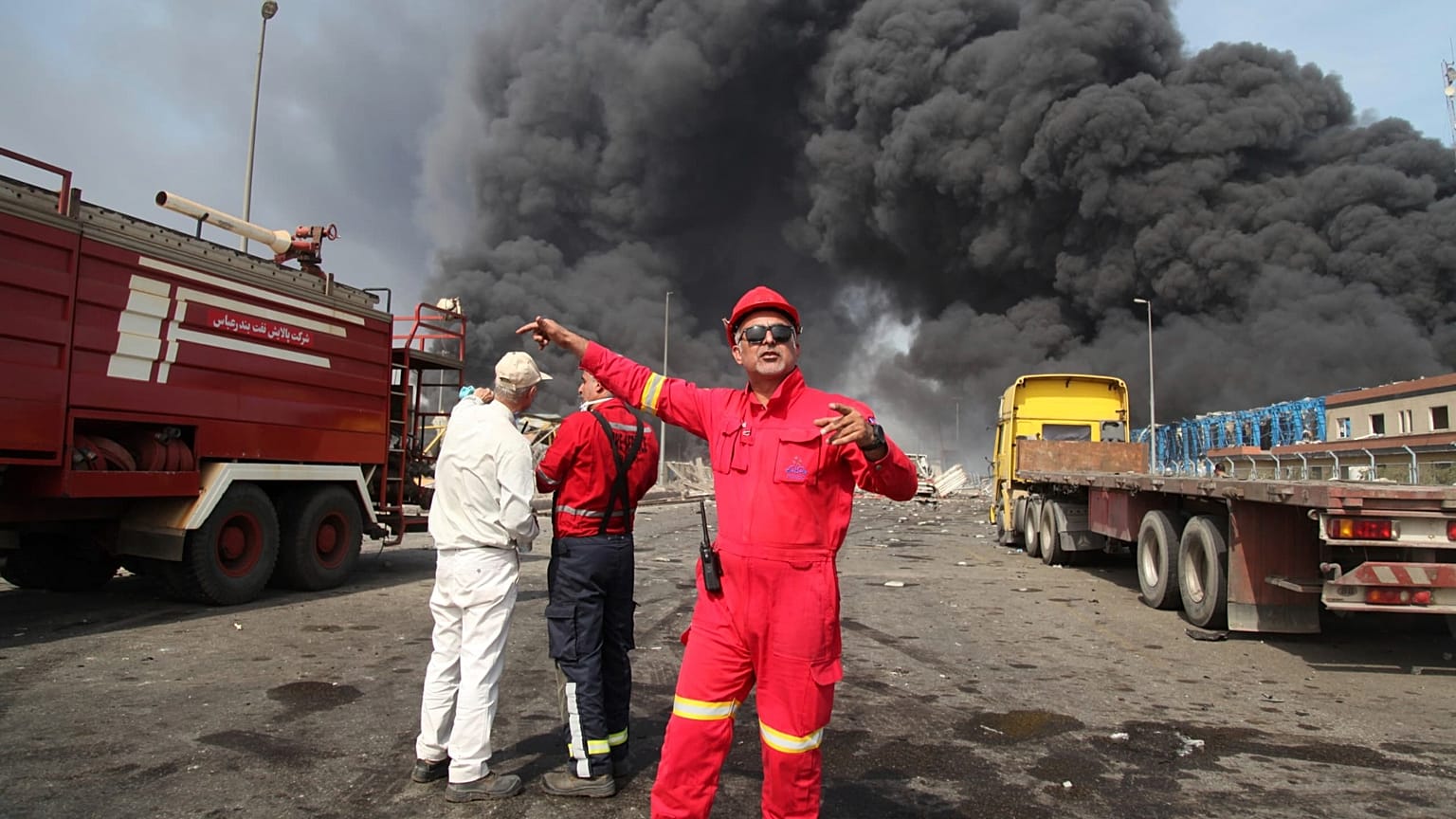 Firefighters work as black smoke rises in the sky after a massive explosion rocked a port near the southern city of Bandar Abbas, 26 April 2025